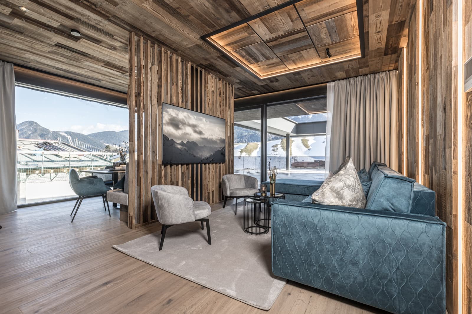 Wohnraum mit Altholzdecke, blauem Sofa und Terrasse mit Bergblick in Wiesing