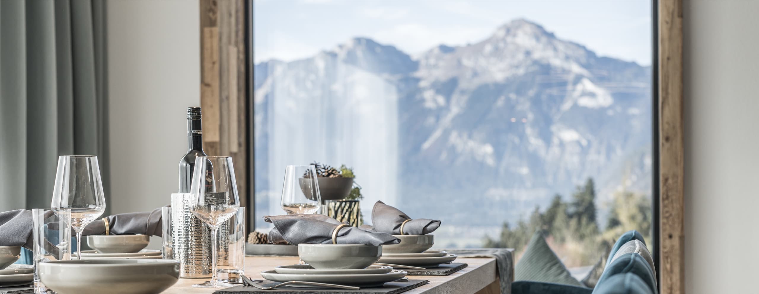 Gedeckter Esstisch vor einem großen Fenster mit Blick auf die Zillertaler Berge